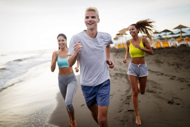 Group of sport people running on the beach