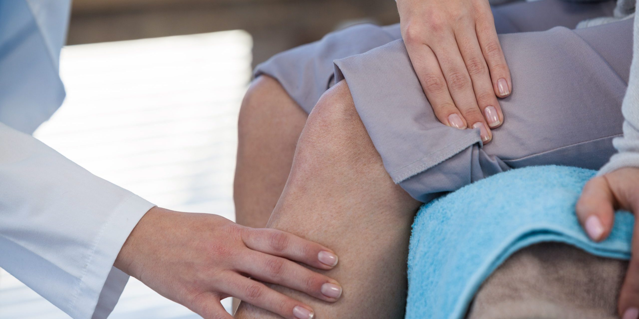 Doctor examining patient knee in clinic